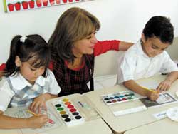 teacher sitting with two children and teaching with love