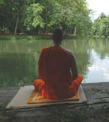 a Buddhist monk meditating near a river bank to find peace within himself