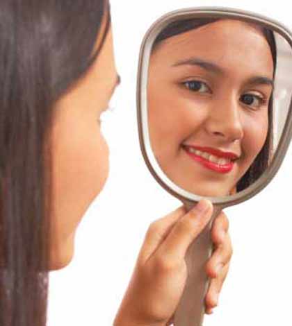 Girl holding mirror and asking am I beautiful with a smile