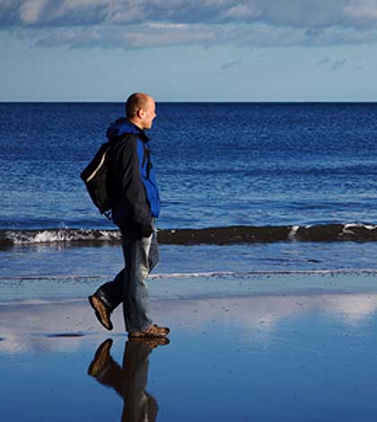 Man walking on the beach trying to make a difference.