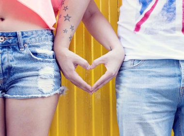 Man and woman making a heart sign with their hands standing side by side