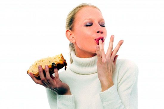 A woman licking fingers as tasty food makes her feel good.