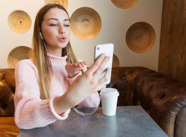 A young woman blowing kiss on mobile cheating on social media