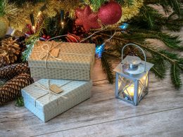 Gifts, lantern, and Christmas tree with decorations on the floor