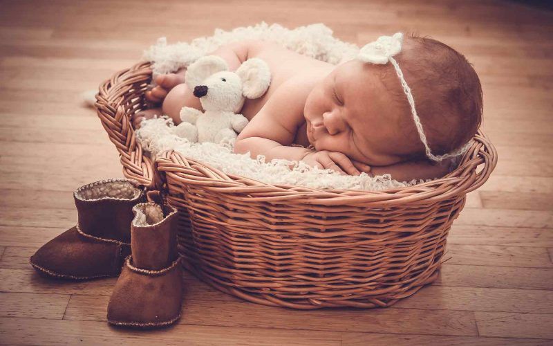 A newborn baby boy in a basket with birthday gifts