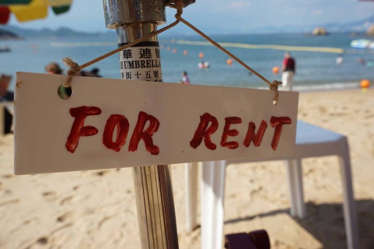 A for rent sign on an umbrella at a beach