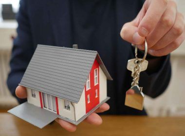 A man with a model of home and a key in hands for renting