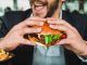 Man eating burger with hands to satisfy hunger or appetite