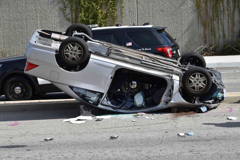 Car lying upside down on road after accident