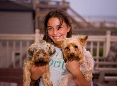 A pet parent woman with two puppies in hand