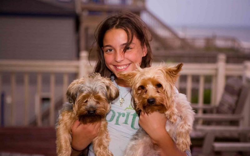 A pet parent woman with two puppies in hand