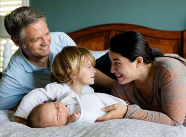 Parents answering small children's questions sitting on bed