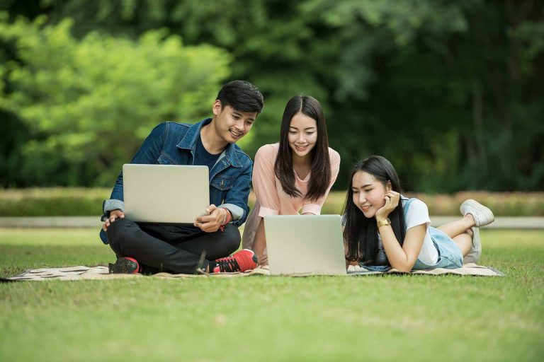 Three young professionals searching for health insurance on laptop