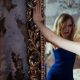 A blonde narcissist woman standing and viewing herself in a mirror