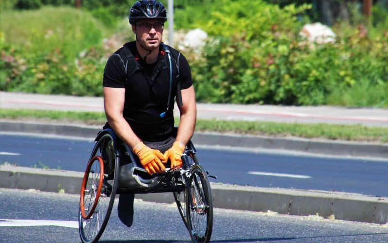 A physically disabled man riding a sports wheelchair.
