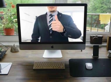 A home office setup at home and a colleague on the monitor screen.