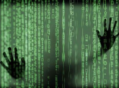 hands of a person trapped behind a green screen of code