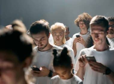 Teens standing in a group and engrossed in their mobiles.